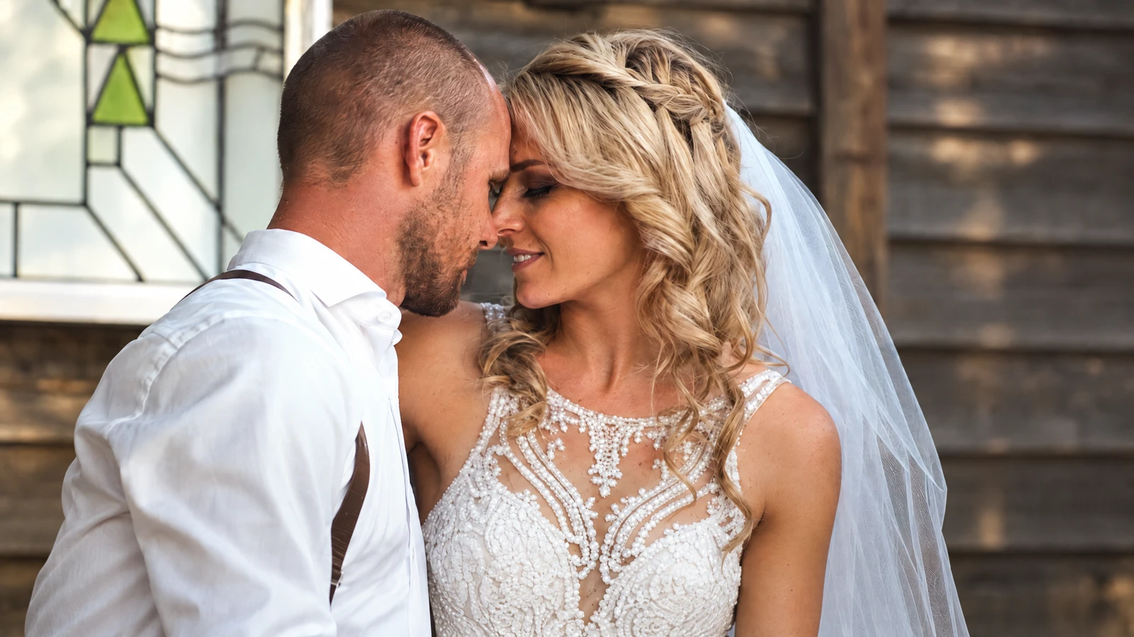 Bride and groom touching foreheads in front of a timber wedding venue, from the Fikri Films Wedding Stories montage